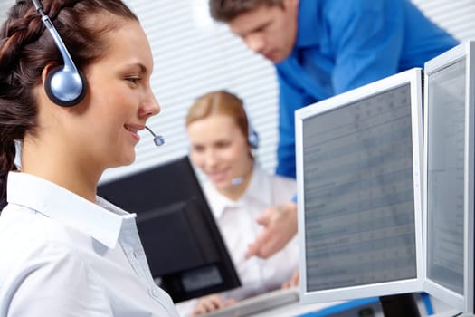 Portrait of consultant speaking by headset and looking at monitor of computer
