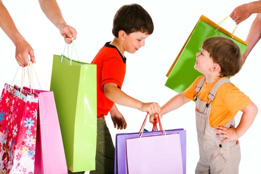 Portrait of two happy boys holding colorful bags between their parents hands