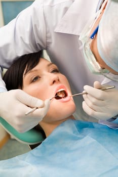Image of young lady with dentist over her checking oral cavity