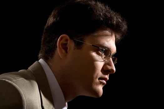 Profile of confident businessman in glasses over black background