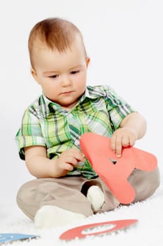 Portrait of baby boy holding paper letter A while making up a word