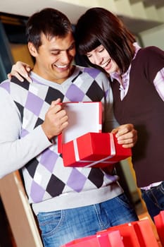 Happy girl and handsome man looking into open red giftbox with smiles