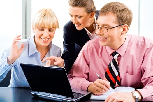 Business woman is explaining the correct way of analysis to his colleagues pointing at the monitor of laptop
