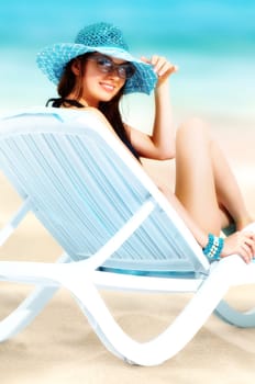 Portrait of a young smiling girl sitting in chaise lounge