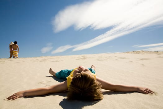 Image of restful boy lying on sand under blue sky and enjoying sunny day
