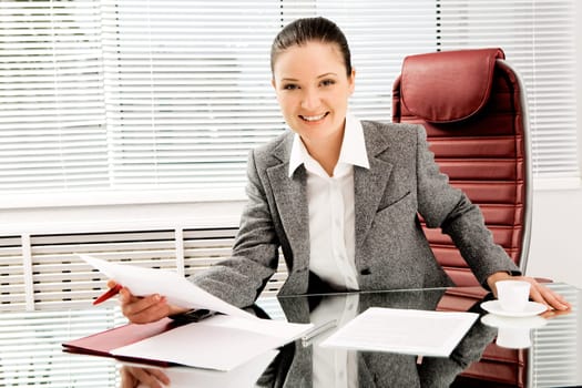 Portrait of happy professional with document in hand looking at camera with smile in office