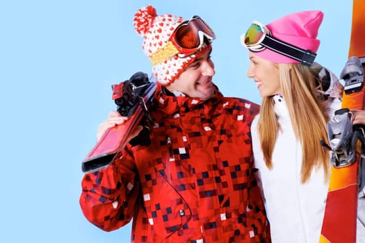 Portrait of happy couple with skis in hands looking at each other and smiling