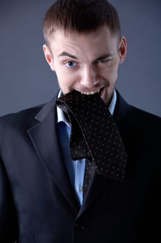 Portrait of odd businessman looking at camera with tie in mouth