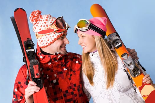 Portrait of happy couple with skis in hands looking at each other and smiling