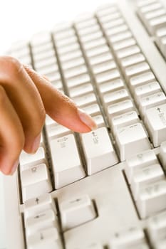 Close-up of female finger on the key of white keyboard