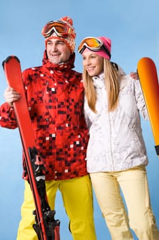 Portrait of happy couple with skis in hands looking aside with smiles
