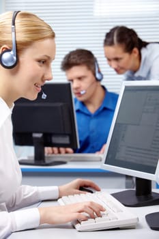 Vertical image of businesswoman consulting by headset during work on the background of businesspeople