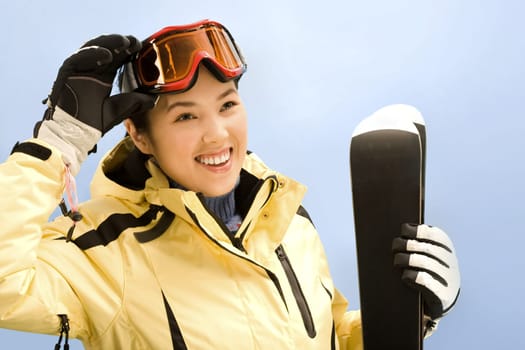 Portrait of sport woman holding her skis and touching glasses