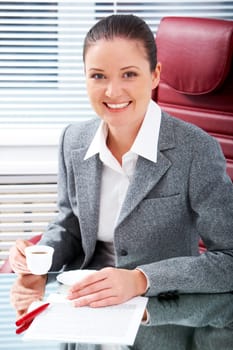 Portrait of happy professional with cup in hand looking at camera with smile in office