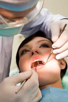 Close-up of woman with open mouth being examined by hygienist