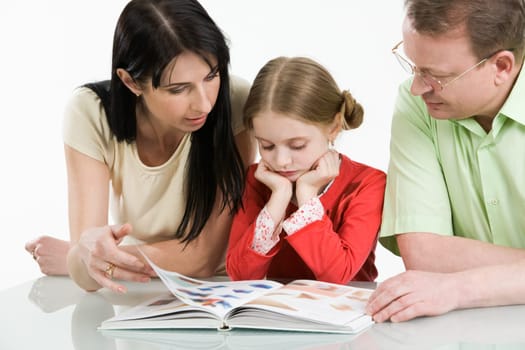 Image of father, mother and their daughter looking through interesting book together