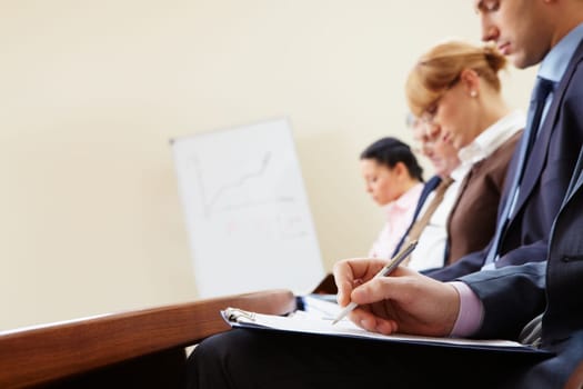 Close-up of businesspeople hands with documents writing at lecture