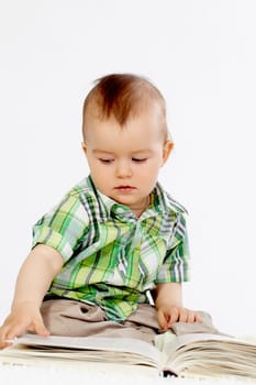 Portrait of baby boy reading book over white background