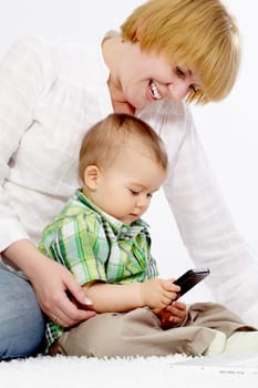 Portrait of baby boy holding cellular phone with his mom near by