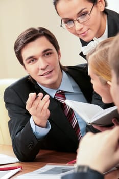 Portrait of handsome businessman explaining something to his colleagues with smart woman near by