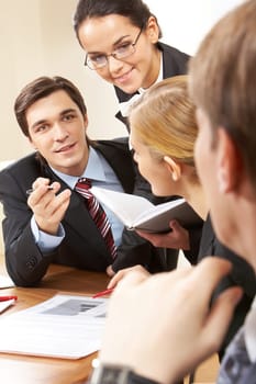 Portrait of handsome businessman explaining something to his colleagues with smart woman near by