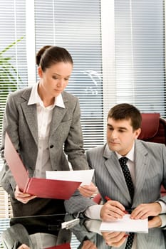 Pretty secretary showing papers to her boss in office