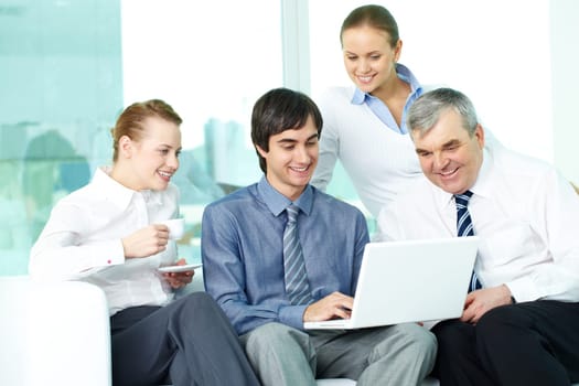 Portrait of several colleagues looking at laptop screen in office