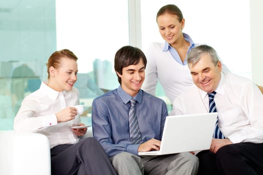 Portrait of several colleagues looking at laptop screen in office