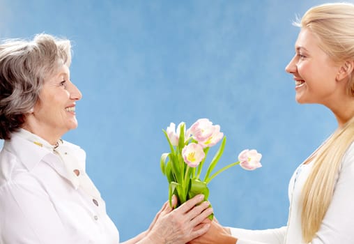 Portrait of young woman giving tulips to her mother