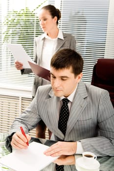 Portrait of serious boss signing contract with executive secretary on background