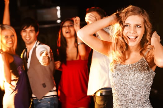 Portrait of joyous girl dancing at party with her friends behind