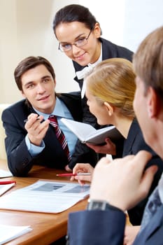 Portrait of handsome businessman explaining something to his colleagues with smart woman near by