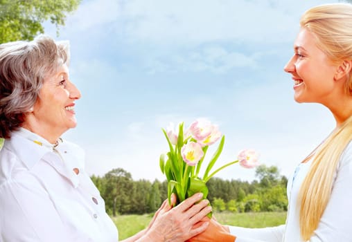 Portrait of young woman giving tulips to her mother