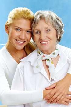 Portrait of attractive daughter hugging mother on a blue background
