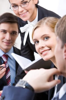 Happy face of pretty employee among her interacting colleagues