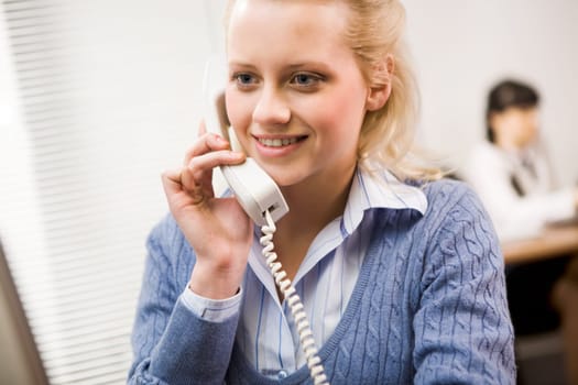 Pretty secretary speaking on the phone in the office