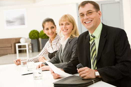 Row of successful business people sitting at the table with man in front