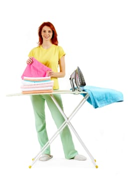 Portrait of young female looking at camera while ironing towels at home