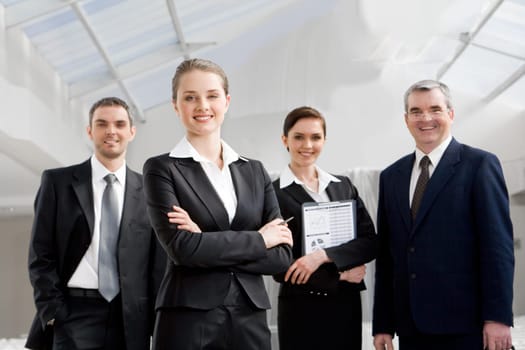 Portrait of smart businesswoman looking at camera at background of co-workers