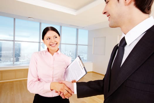 Photo of happy partners handshaking after signing contract