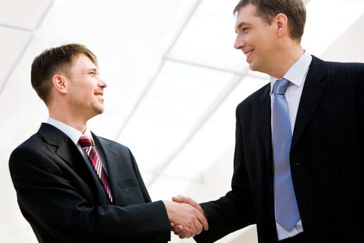 Portrait of two happy businessmen handshaking after striking promising deal