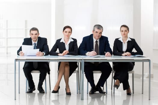 Portrait of smart business people sitting at table and looking at camera