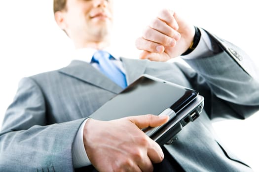 View from below of a businessman with laptop looking at his watch