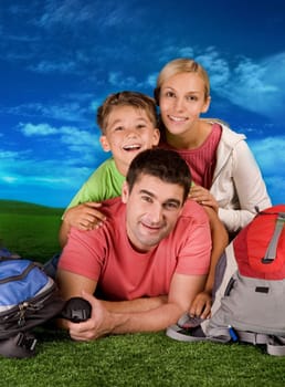 Portrait of family lying on grassland during rest over blue sky background