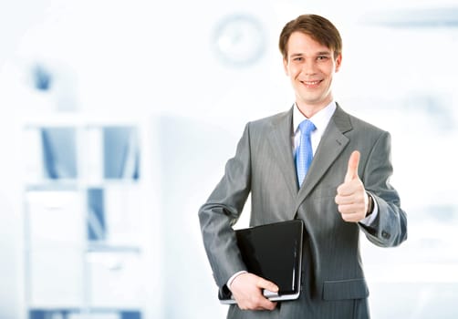 Portrait of happy businessman holding the laptop and showing thumb up