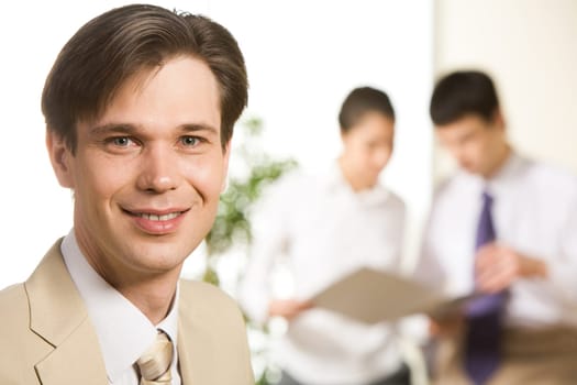 Portrait of confident businessman looking at camera on the background of coworkers