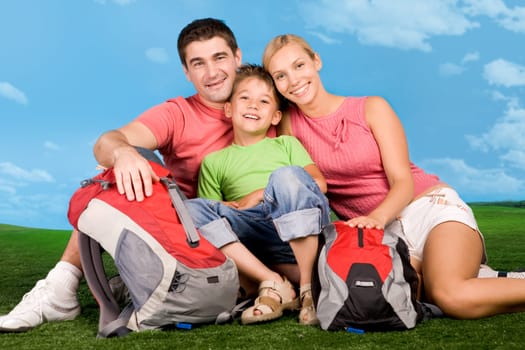 Portrait of family lying on grassland during rest over blue sky background