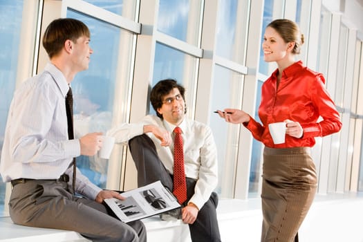 Portrait of businesswoman holding cup and explaining new project to businessmen