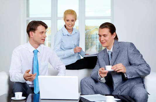 Portrait of successful co-workers sharing their ideas near laptop at meeting