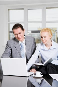 Portrait of friendly workteam looking at monitor of laptop and discussing something